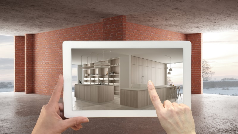 A Picture Of A Tablet Being Held Up To A Blank, Corner Background Setting. The Tablet, However, Is Showing Furniture Instead Of The Blank Canvas - Which Is Showcasing Augmented Reality.